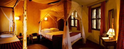 a bedroom with a canopy bed and two windows at NSYA CAMP MANYARA in Mto wa Mbu