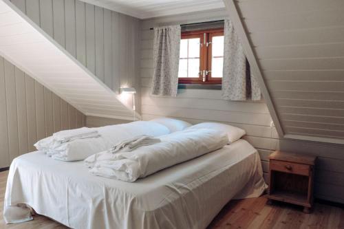 1 cama con sábanas blancas en una habitación en Hunderfossen Apartments en Hafjell