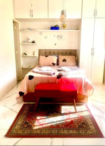 uma cama com um banco vermelho num quarto em Apartamento área nobre em Petrópolis