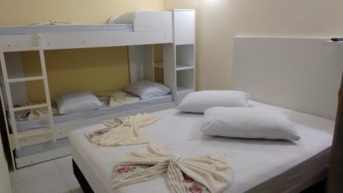 two bunk beds with white pillows in a room at Apto e Suítes Praia do Itapocoroi in Penha