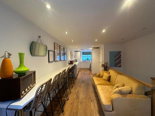 a living room with a long couch and chairs at Luxury Retro 4 Bed Town House in heart of Alnwick in Alnwick