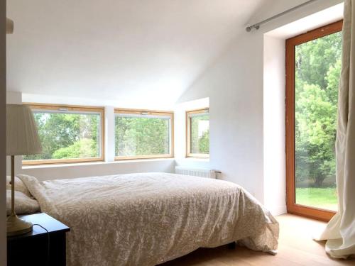 une chambre blanche avec un lit et deux fenêtres dans l'établissement Ensemble de Maisons avec Vue sur la Nature, à Bains-sur-Oust