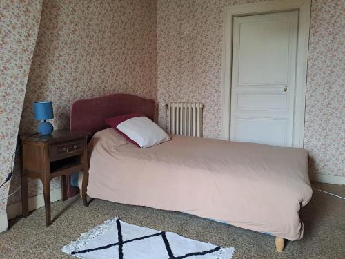 1 dormitorio con cama, mesa y puerta en cosy vintage room, en Châteauroux