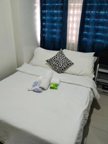 a white bed with white pillows and a green bottle on it at Nicecondotel in Manila