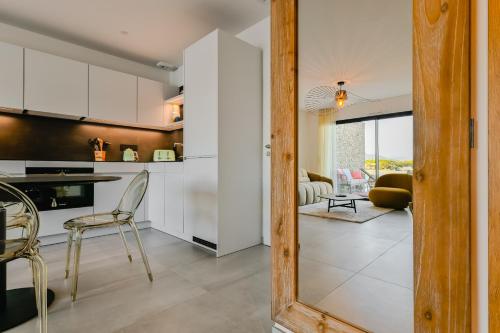 une cuisine avec des armoires blanches et une table et des chaises dans l'établissement T2 LUXE Pieds dans l'eau Porticcio, à Grosseto-Prugna