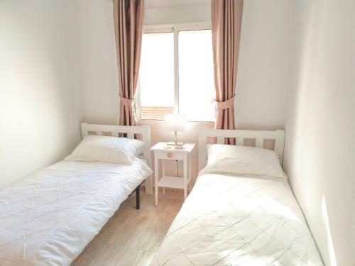 twee bedden in een kleine kamer met een raam bij Villa Casa Max - duplex-apartment in Villamartin Golf Resort in Villamartin