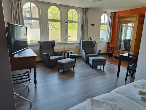 een kamer met stoelen, een bed en een tv bij Hotel Saint Vincent in Poeldijk