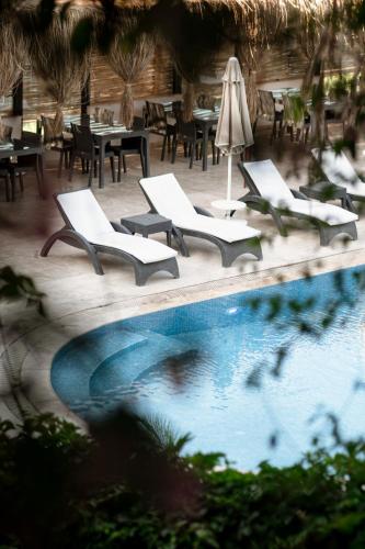 a swimming pool with lounge chairs and tables and a restaurant at Mare Garden Hotel in Akyarlar