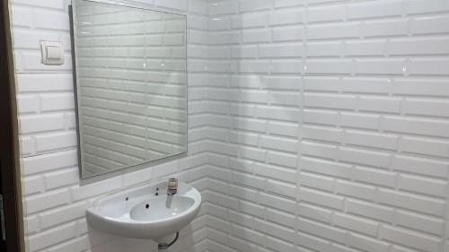ein weißes Badezimmer mit einem Waschbecken und einem Spiegel in der Unterkunft tekMIRA Hotel in Bandung