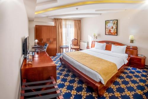 Habitación de hotel con cama y escritorio con TV. en Cron Palace kosher Tbilisi Hotel, en Tiflis