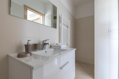 een witte badkamer met een wastafel en een spiegel bij Villa Bumortu in Olmeto