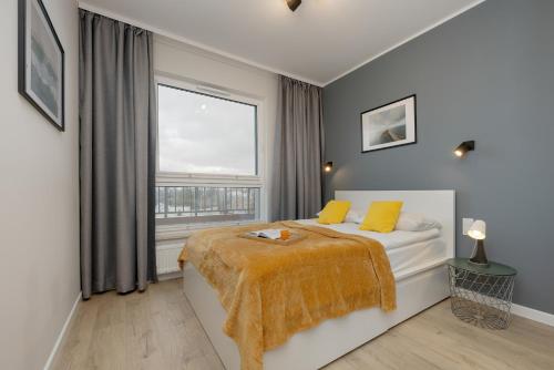 - une chambre avec un lit doté d'oreillers jaunes et d'une fenêtre dans l'établissement Unique Szczesliwa Apartment with Balcony Parking and AC by Renters, à Gdańsk