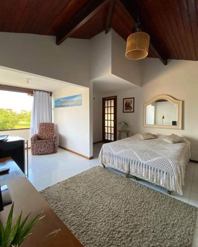a bedroom with a bed and a chair and a mirror at Deu praiabuzios in Búzios