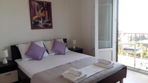a bedroom with a bed with purple pillows and a balcony at Apartments Vucetic in Hvar