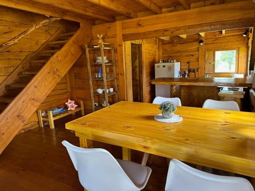 comedor con mesa de madera y sillas blancas en Cabaña Guanumby en Tandil