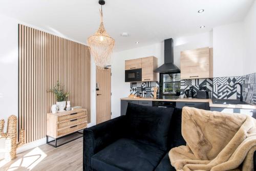 a living room with a black couch and a kitchen at Railway Apartments Rugby in Rugby