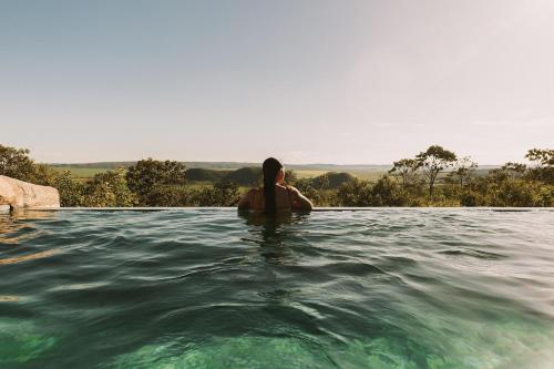 un uomo seduto in acqua in una piscina di Casa Ônix View (15km AltoParaíso) - Viagem Inspirada a São João da Aliança