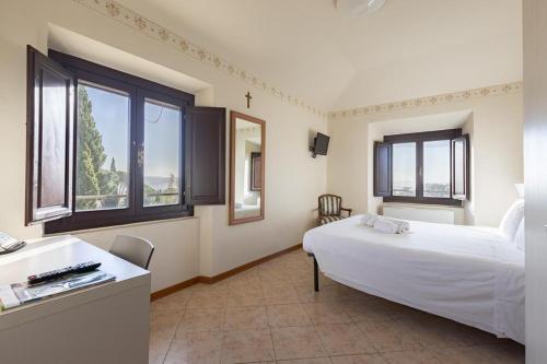 1 dormitorio con 1 cama blanca grande y ventanas en Villa La Stella, en Florencia