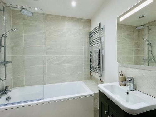 uma casa de banho com uma banheira, um lavatório e um chuveiro em Coastal Cottage with hot tub, sleeps 10 em Bacton