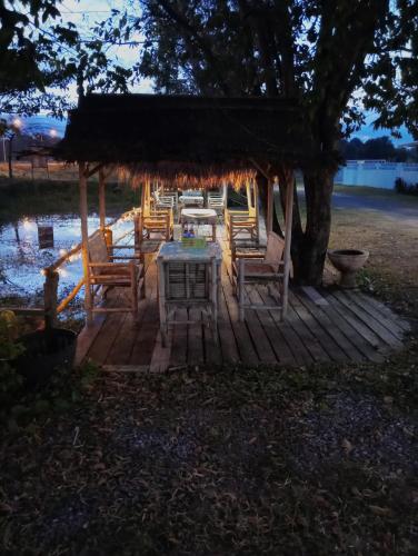 une table et des chaises sur une terrasse en bois avec un arbre dans l'établissement River restaurant&room service อาหารตามสั่ง&ห้องพักรายวัน, à Prasat