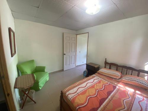 a bedroom with a bed and a green chair at Acogedora vivienda anexa en un barrio tranquilo in David