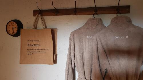 a clock and two shirts hanging on a wall at Le Lodge des Flâneurs in Vielsalm