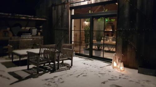 a patio with two benches in the snow at Le Lodge des Flâneurs in Vielsalm