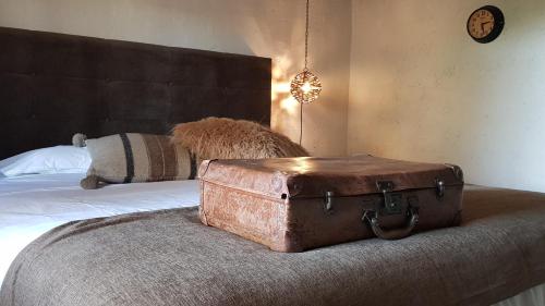 an old suitcase sitting on top of a bed at Le Lodge des Flâneurs in Vielsalm