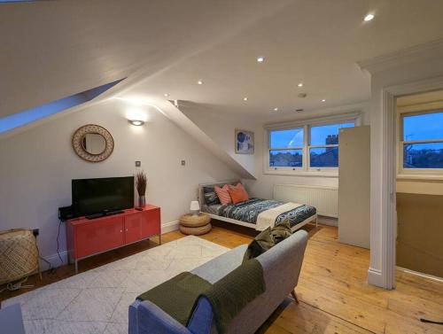 a living room with a couch and a tv at Fabulous Studio Retreat - Flat 4 Highbury in London