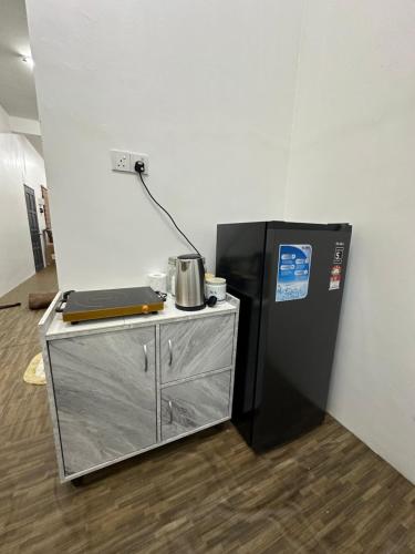 a room with a refrigerator and a table with a microwave at Seriemas Angler Venture Homestay in Sepang