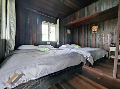 - 2 lits dans une chambre dotée de murs en bois dans l'établissement Tim Seaside Resort by Evernent, à Miri