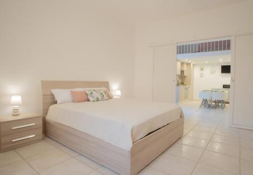a white bedroom with a large bed and a kitchen at TREVVOLTE Apulian Apartments in Mesagne