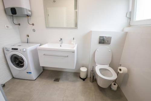a bathroom with a toilet and a sink and a washing machine at Luxury Apartment Marija in Novalja