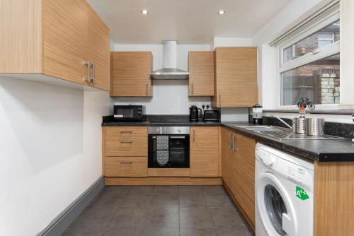 a kitchen with wooden cabinets and a washer and dryer at Charming 5-Bedrooms in the Heart of Liverpool - By Resify in Liverpool