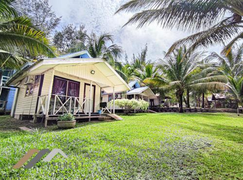 une petite maison dans une cour avec des palmiers dans l'établissement Tim Seaside Resort by Evernent, à Miri