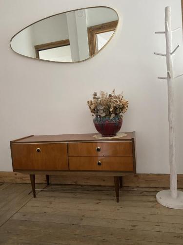 a dresser with a mirror and a vase with flowers on it at Rétro Studio in Brussels