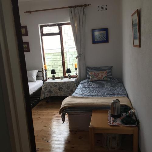 a bedroom with a bed and a table and a window at Prestone Cottage in Cape Town