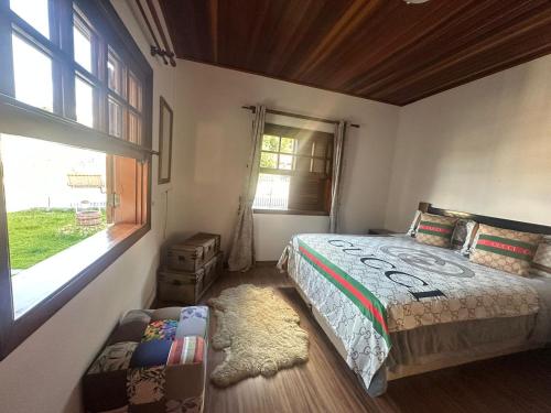 um quarto com uma cama e uma janela em Recanto do Aconchego em Campos do Jordão