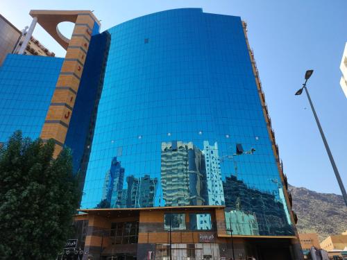 a glass building with a reflection of a city at فندق إي دبليو جي العزيزية in Mecca