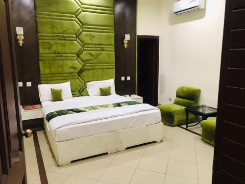 a bedroom with a bed and a green wall at Hotel PAK Continental Multan in Multan