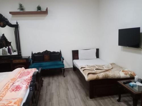 1 dormitorio con 2 camas y TV en la pared en Hotel PAK Continental Multan en Multán