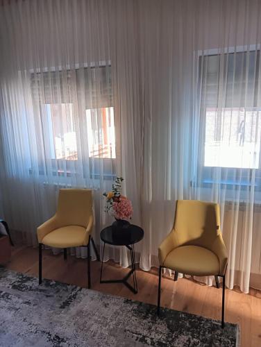 two chairs and a table in a room with windows at Anais Chalet in Câmpulung Moldovenesc