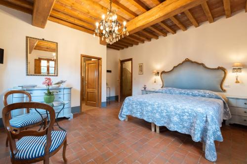 a bedroom with a bed and a table and a chandelier at Agriturismo La Valle A Polvereto in Tavarnelle Val di Pesa