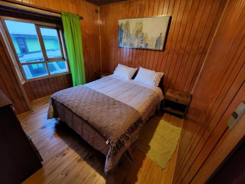 een slaapkamer met een bed met een groen gordijn bij Cabañas Quetalmahue in Ancud
