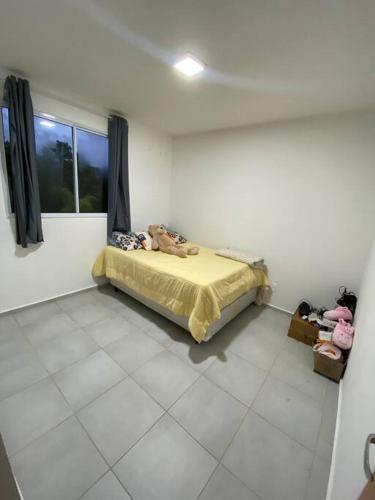 a bedroom with a bed in a room with a window at Apartamento para alugar in Biguaçu