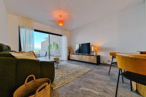a living room with a couch and a television at Le Galatée ,T2 luxe pieds dans l'eau in Porticcio