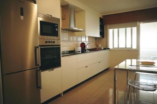 a kitchen with white cabinets and a stainless steel refrigerator at Rosende VUT in Arz&uacute;a