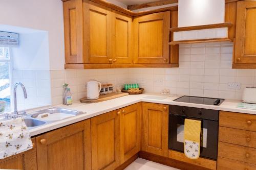 a kitchen with wooden cabinets and a sink at Gardener's Cottage in Lancaster