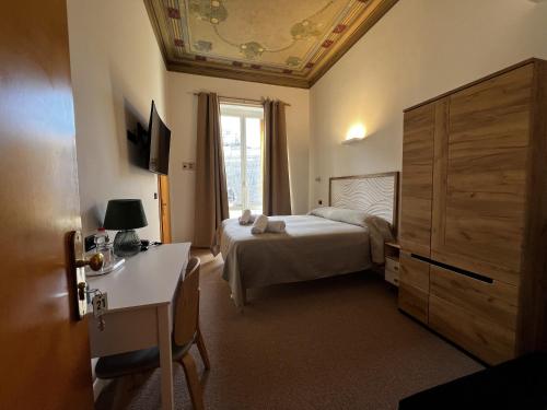 Schlafzimmer mit einem Bett, einem Schreibtisch und einem Fenster in der Unterkunft Hotel Genova Liberty in Genua