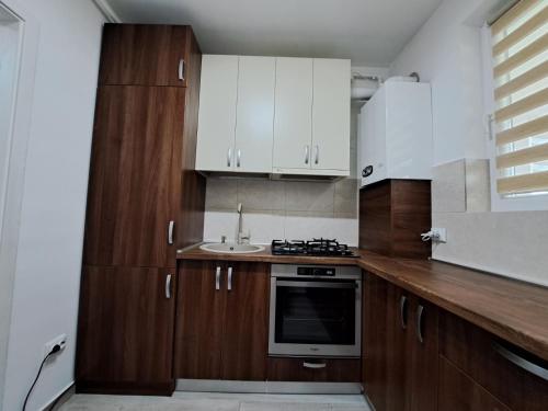 a small kitchen with wooden cabinets and a sink at Siena Cozy retreat with self check in in Popeşti-Leordeni